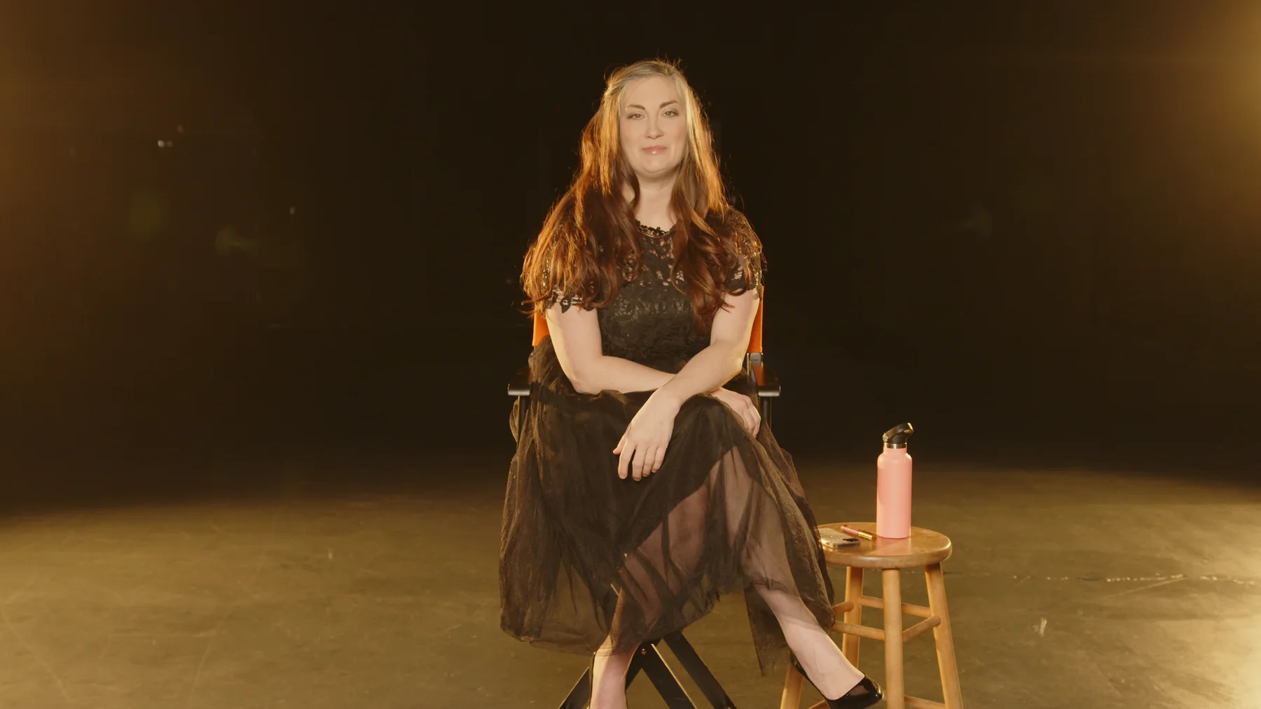 Amie Roussel seated in a warm studio setup during a photography brand video.