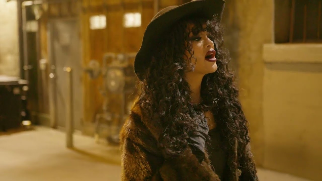 Alexandra Wright performs in a black cowboy hat under warm cinematic light.