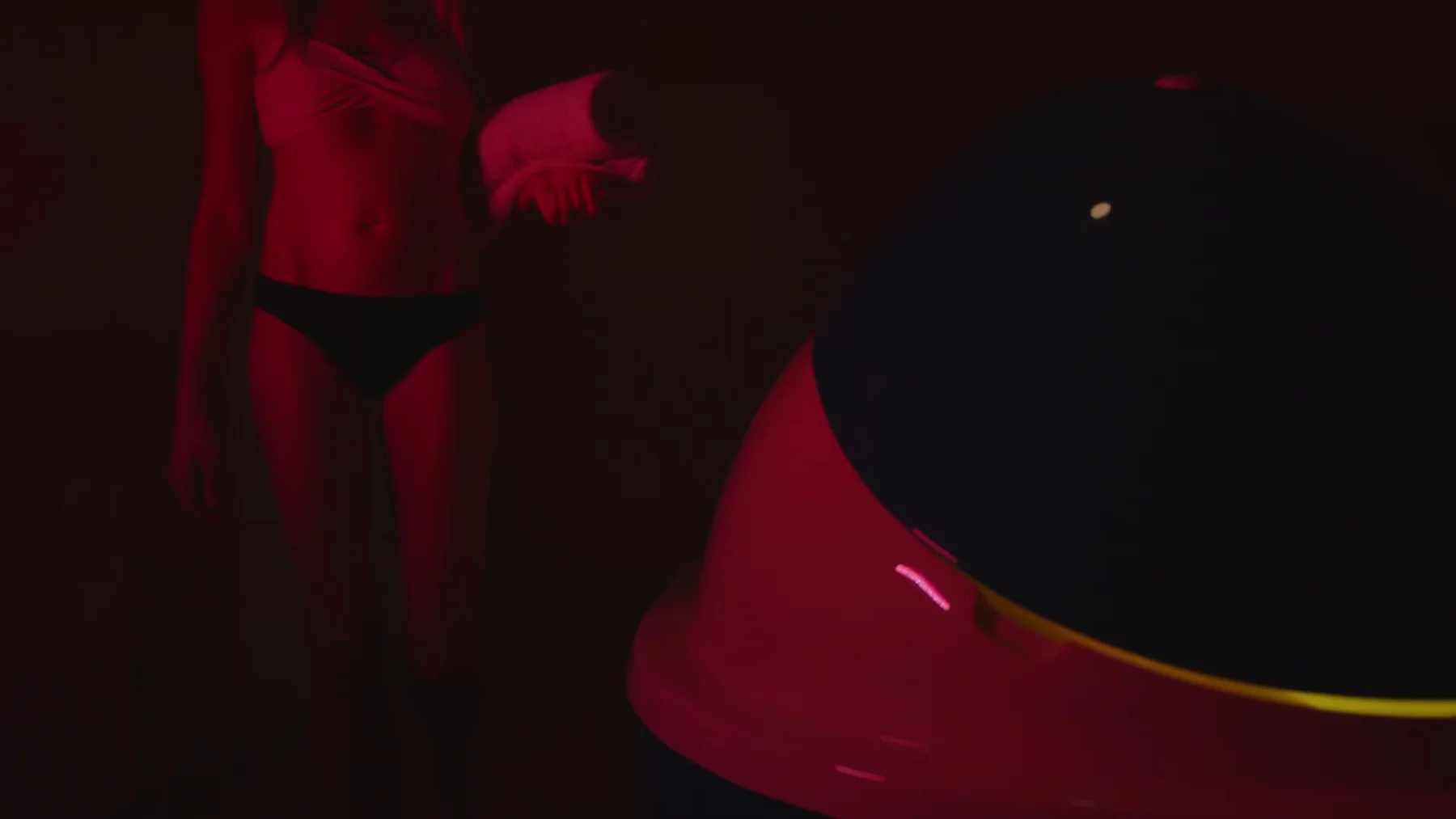A person stands beside an open float pod under red light.
