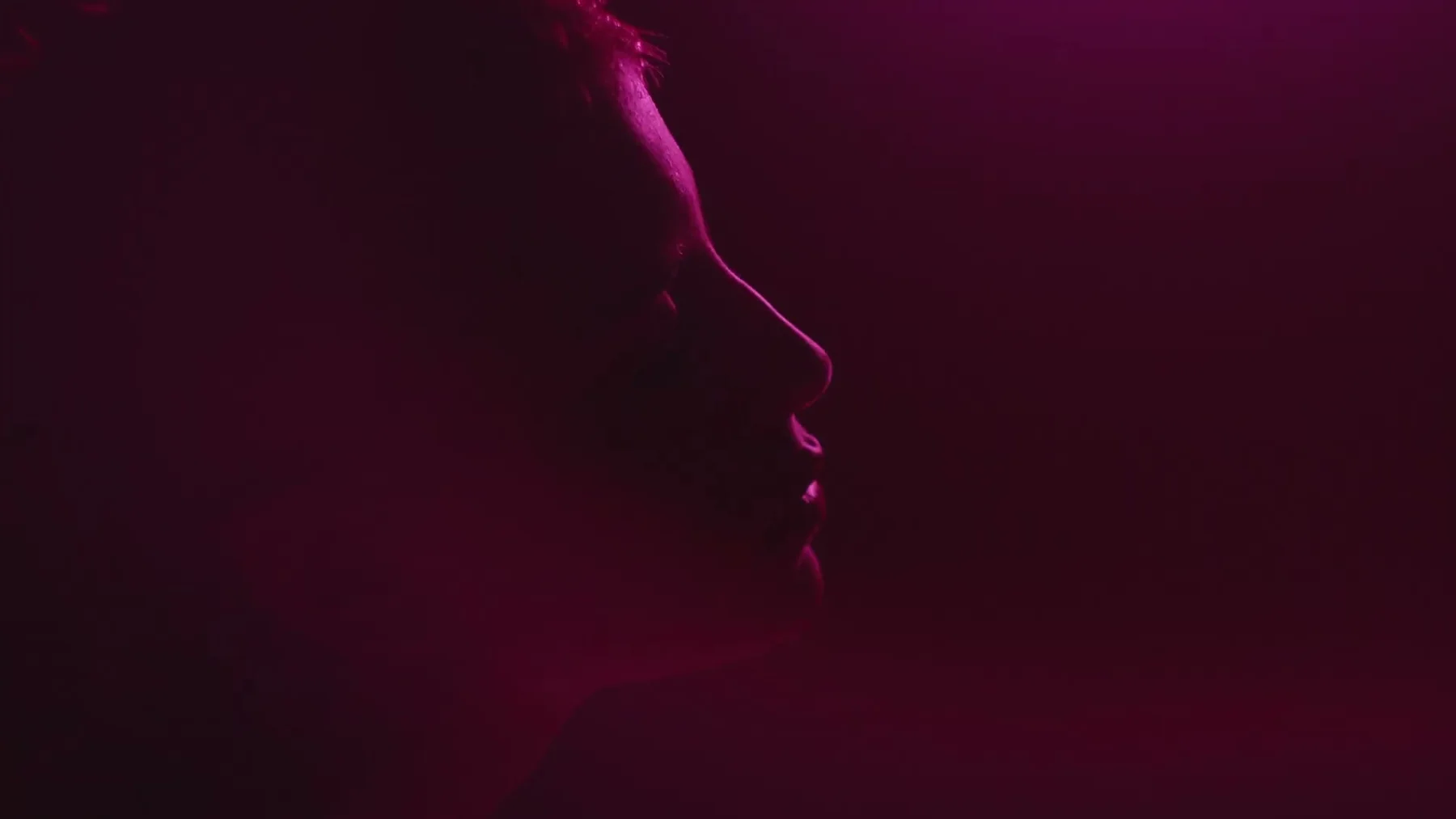 A man's profile is outlined in magenta light.