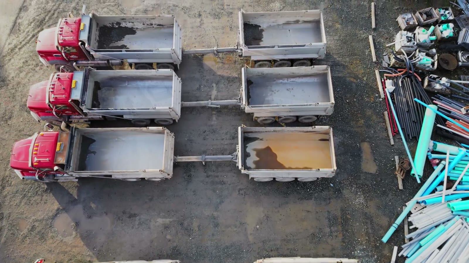 Top-down drone frame of dump trucks and site materials at the High Road jobsite.