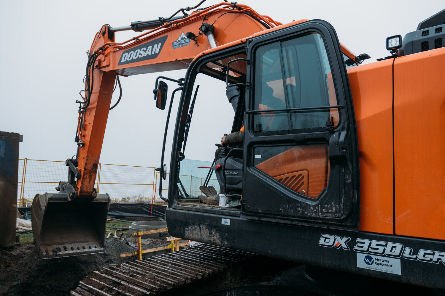Operator working inside a High Road excavator on site.