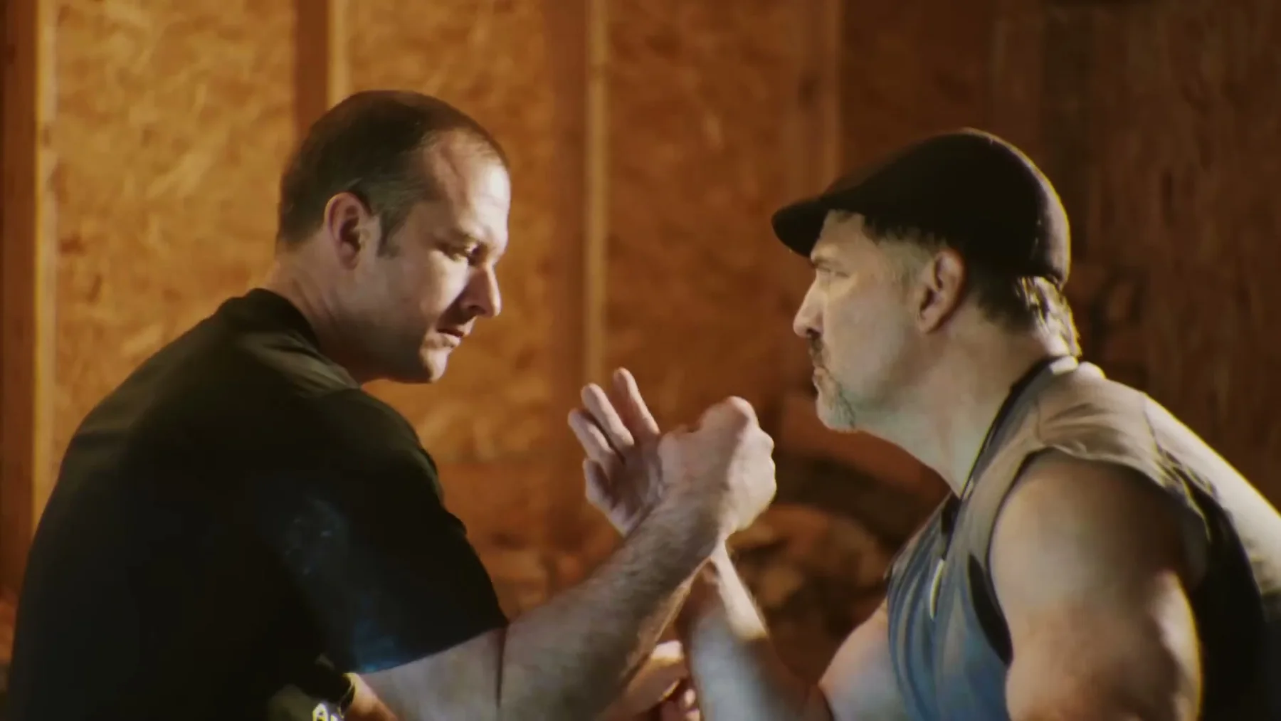 Two men lean into an arm-wrestling match.
