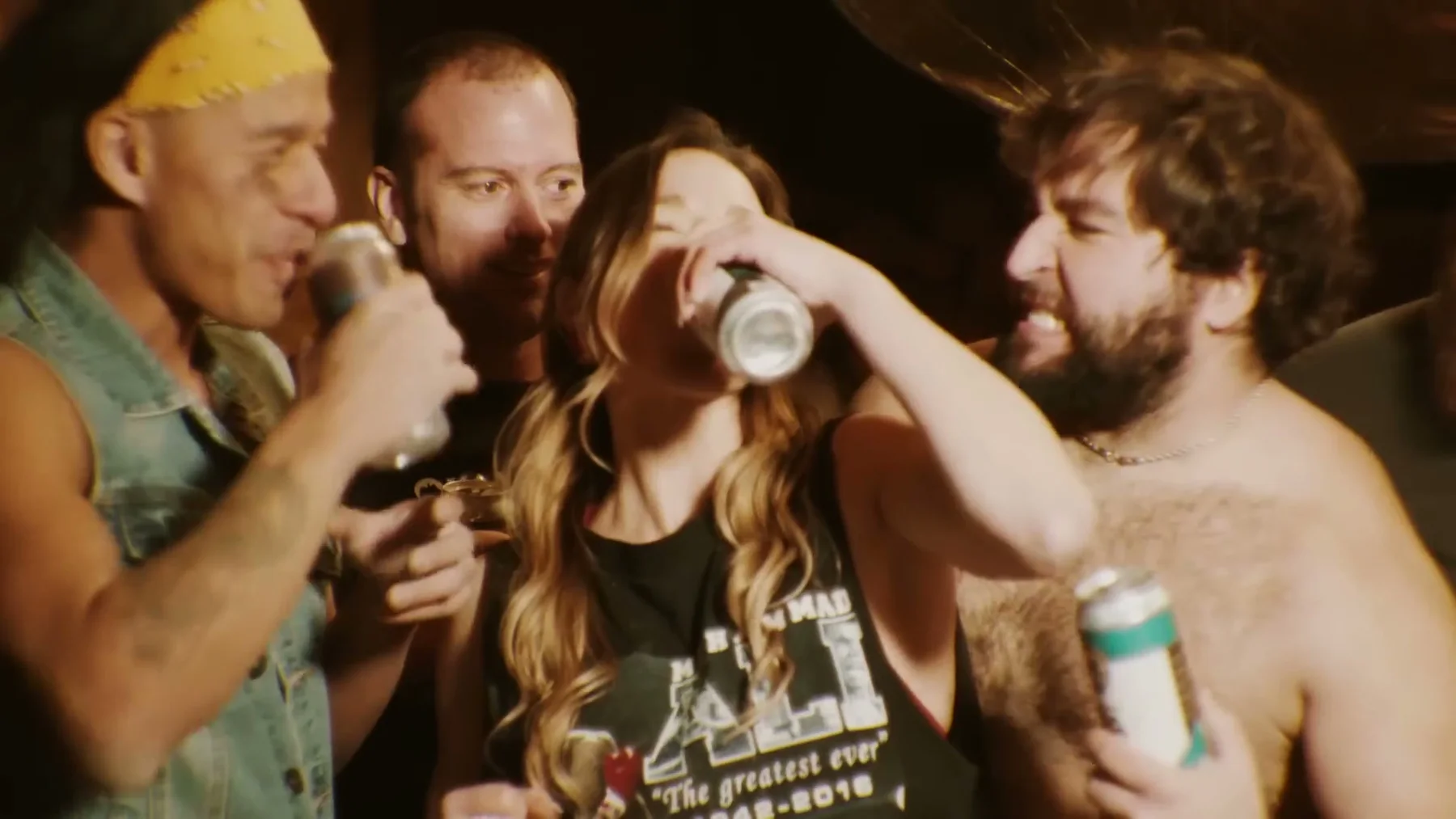 A group raises drink cans together inside a wooden room.