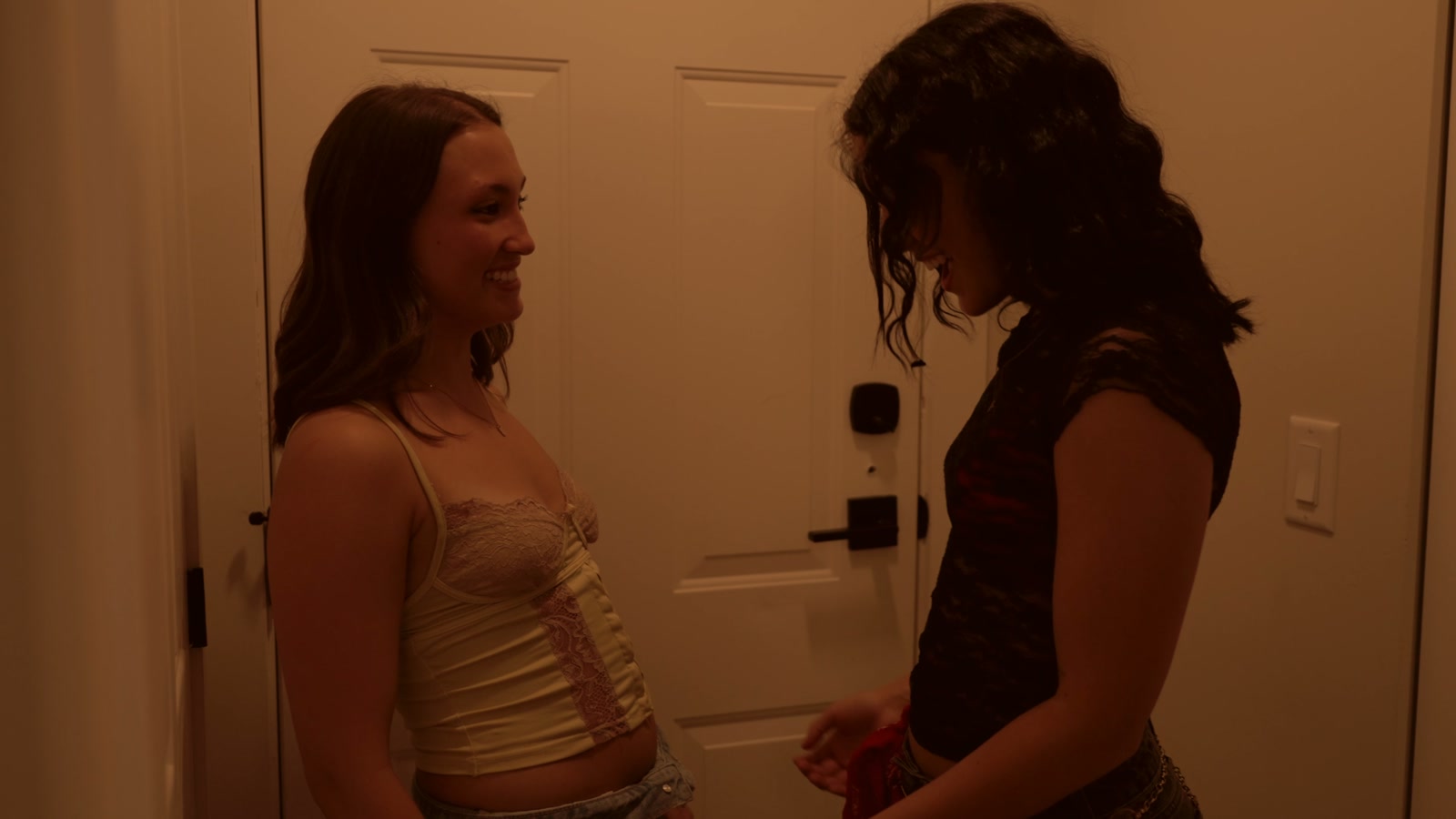 The two leads facing each other beside an apartment doorway.