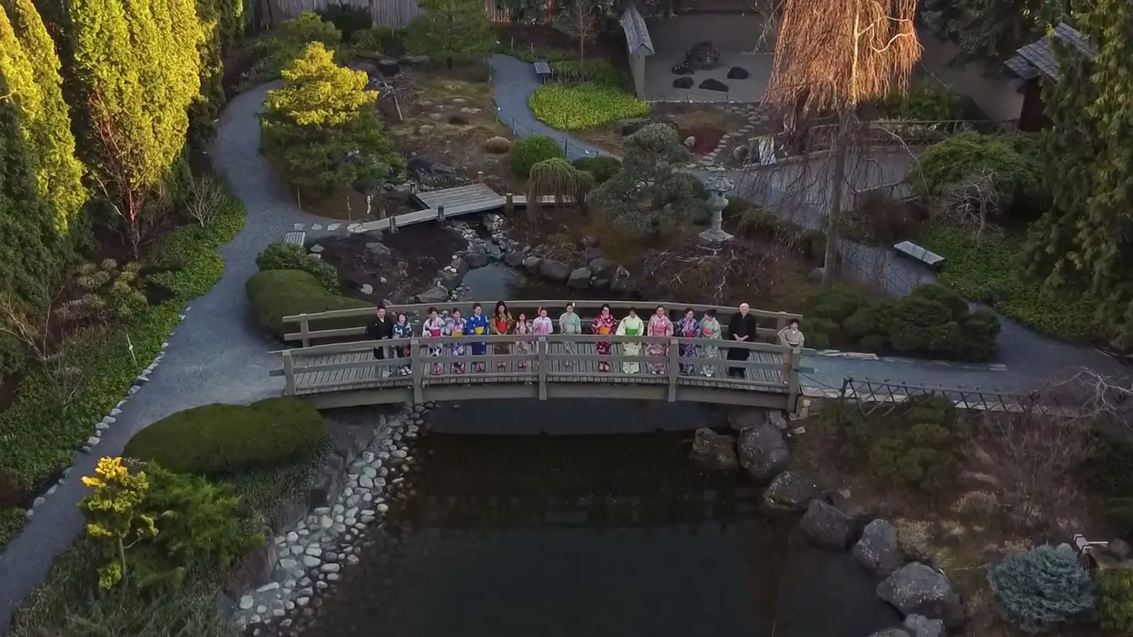 A group gathers on a bridge above the pond in Kasugai Gardens.