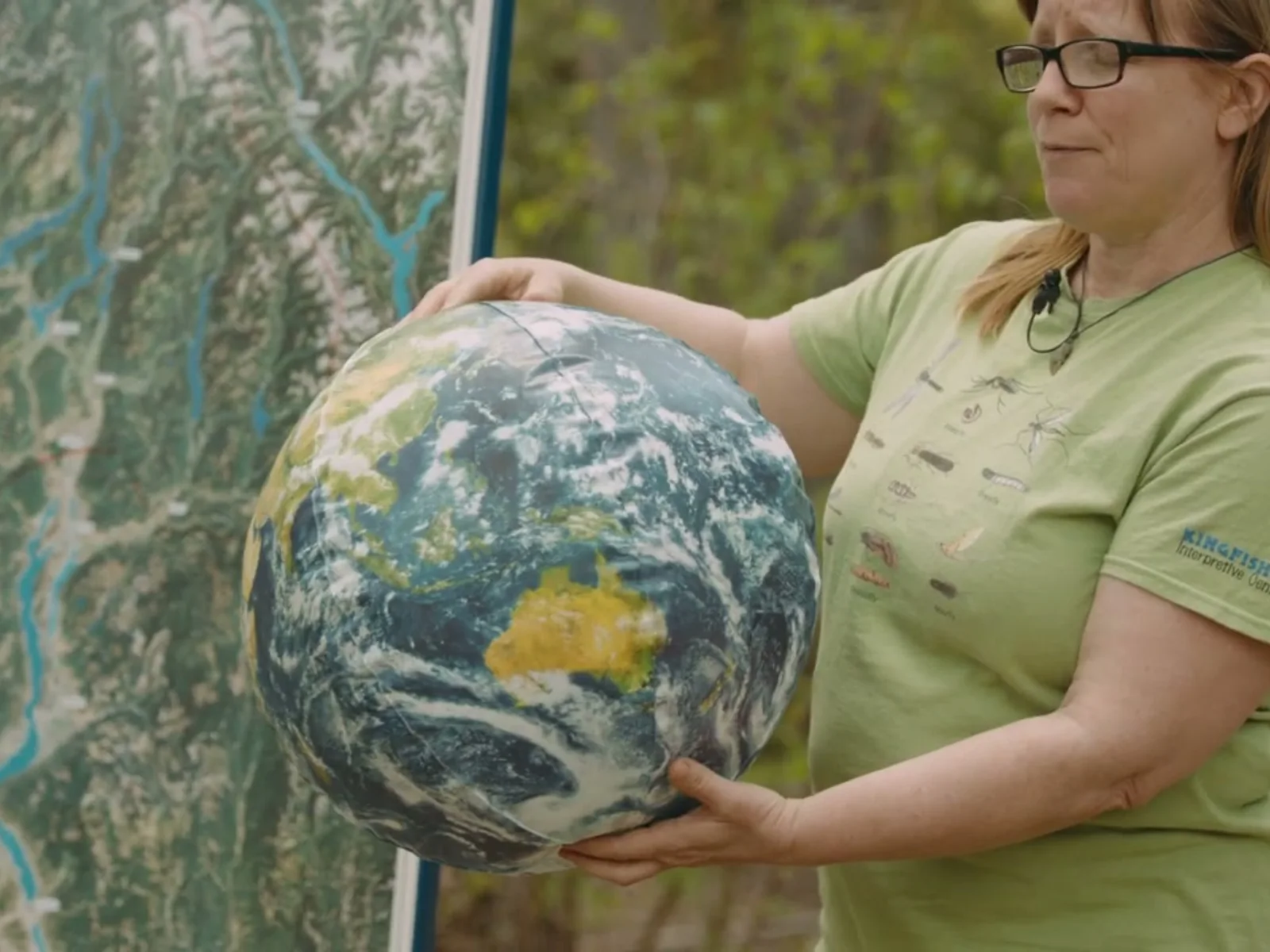 Molly Cooperman explaining watershed systems with a map and globe.