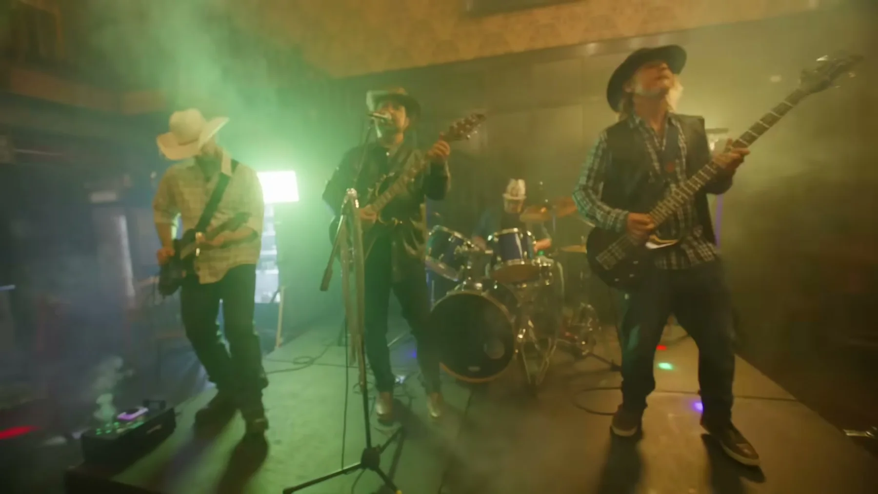 A country band performs under green and amber stage light.