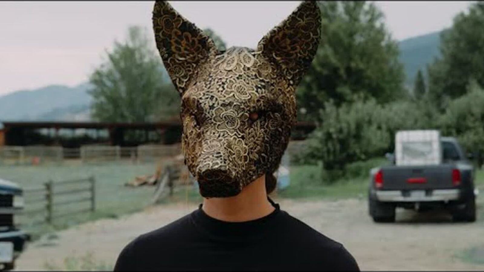 A masked figure stands in a rural Naramata landscape from Autumn Sun.