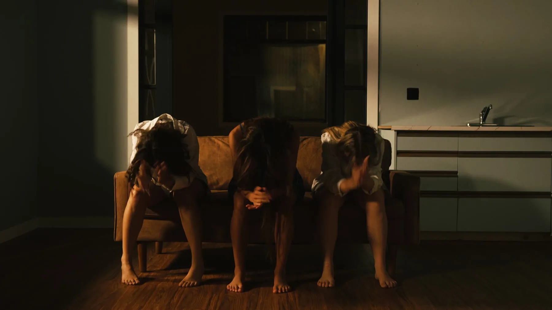 Three dancers seated on a couch during Vienna Hank's choreography film.