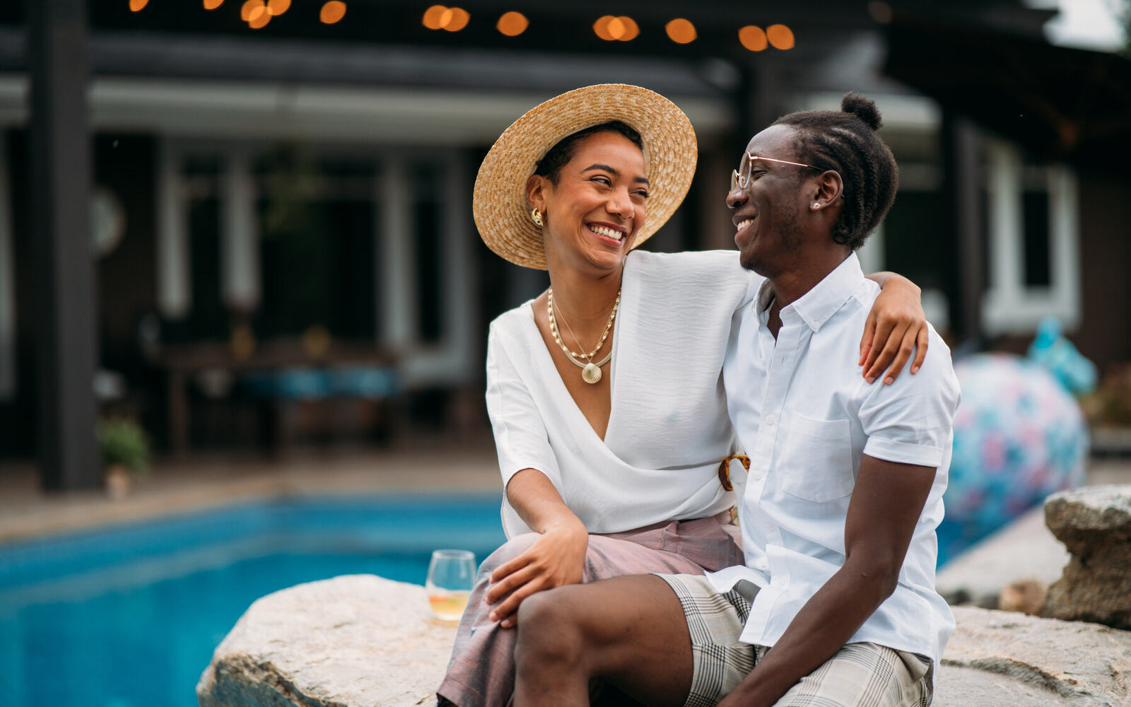 Two Zeff models sit together beside a pool in polished lifestyle campaign photography.